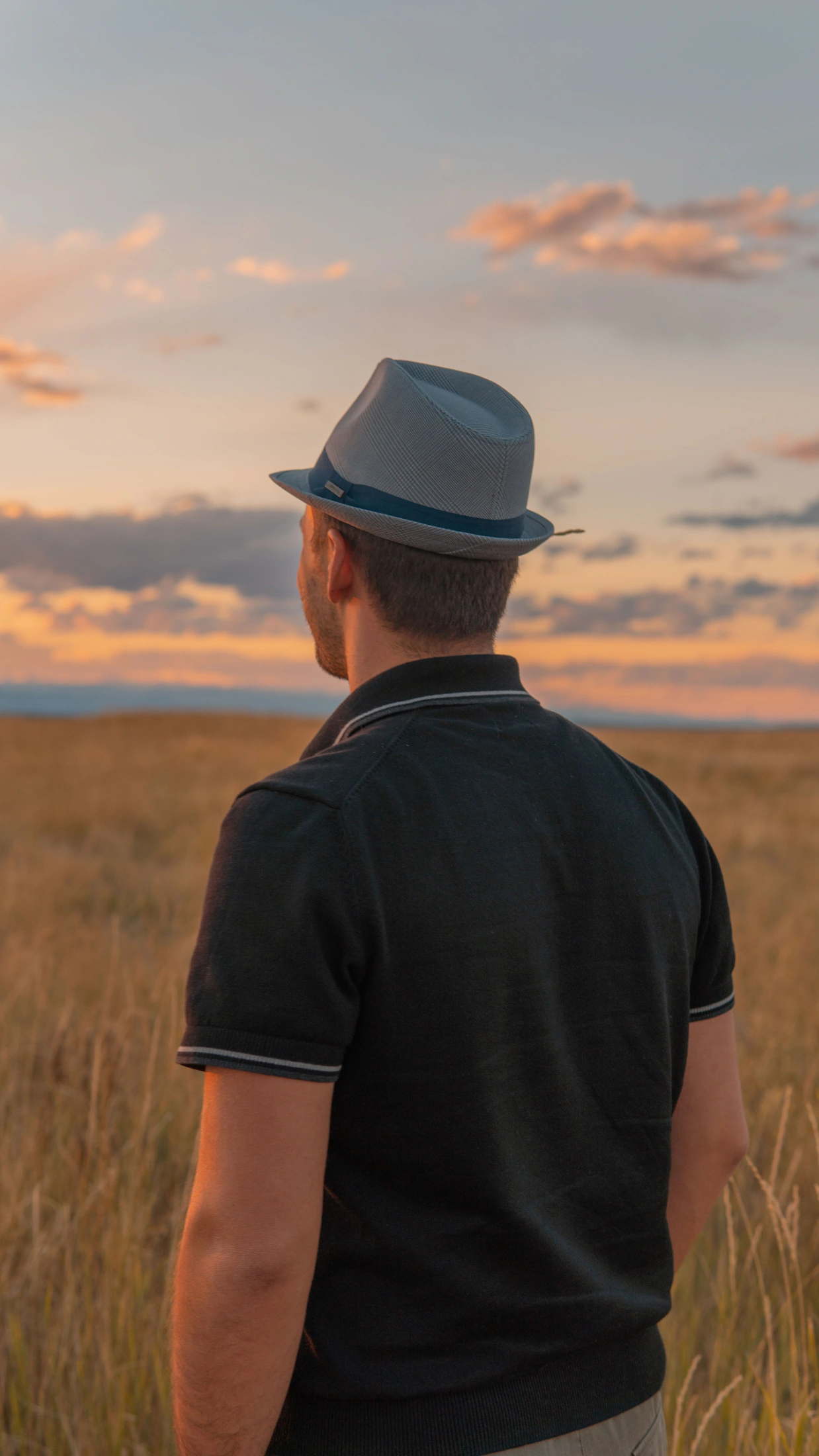 Man in a hat standing in a golden field at sunset